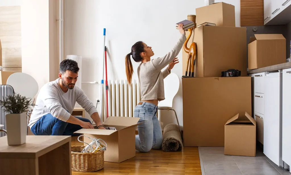 a couple helping each other to packing household material